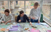 a group of women are making paper crafts at a table