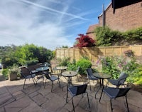 a patio area with tables and chairs in a garden