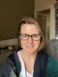 a woman in glasses smiling in a living room