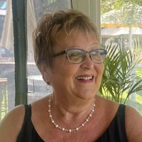 an older woman with glasses smiling at a table