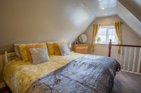 a bed in an attic room with a yellow comforter