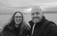 a man and woman taking a selfie in front of a body of water