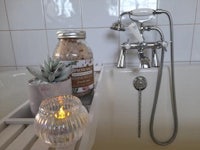 a bath tub with a candle and jar of bath salts