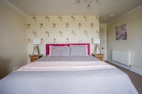 a bedroom with a pink bed and floral wallpaper