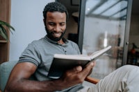 a black man reading a book while sitting in a chair