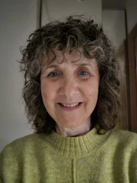 a woman in a green sweater smiles for the camera